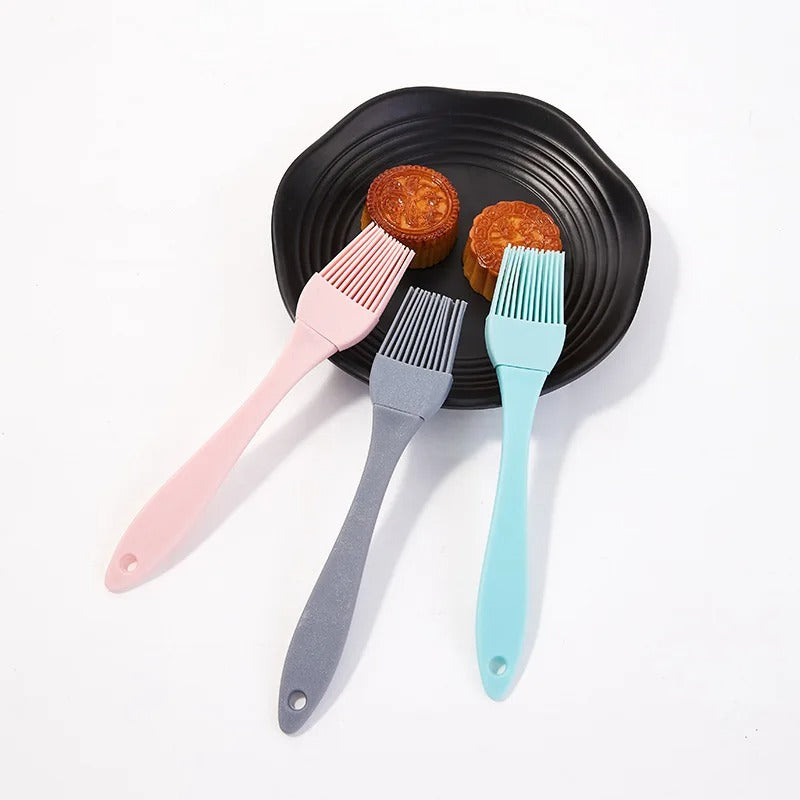 Trois pinceaux de cuisine en silicone sur une assiette noire, parfaits pour les pâtisseries et la cuisine