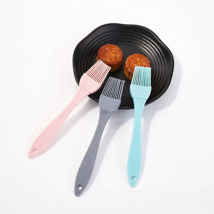 Trois pinceaux de cuisine en silicone sur une assiette noire, parfaits pour les pâtisseries et la cuisine