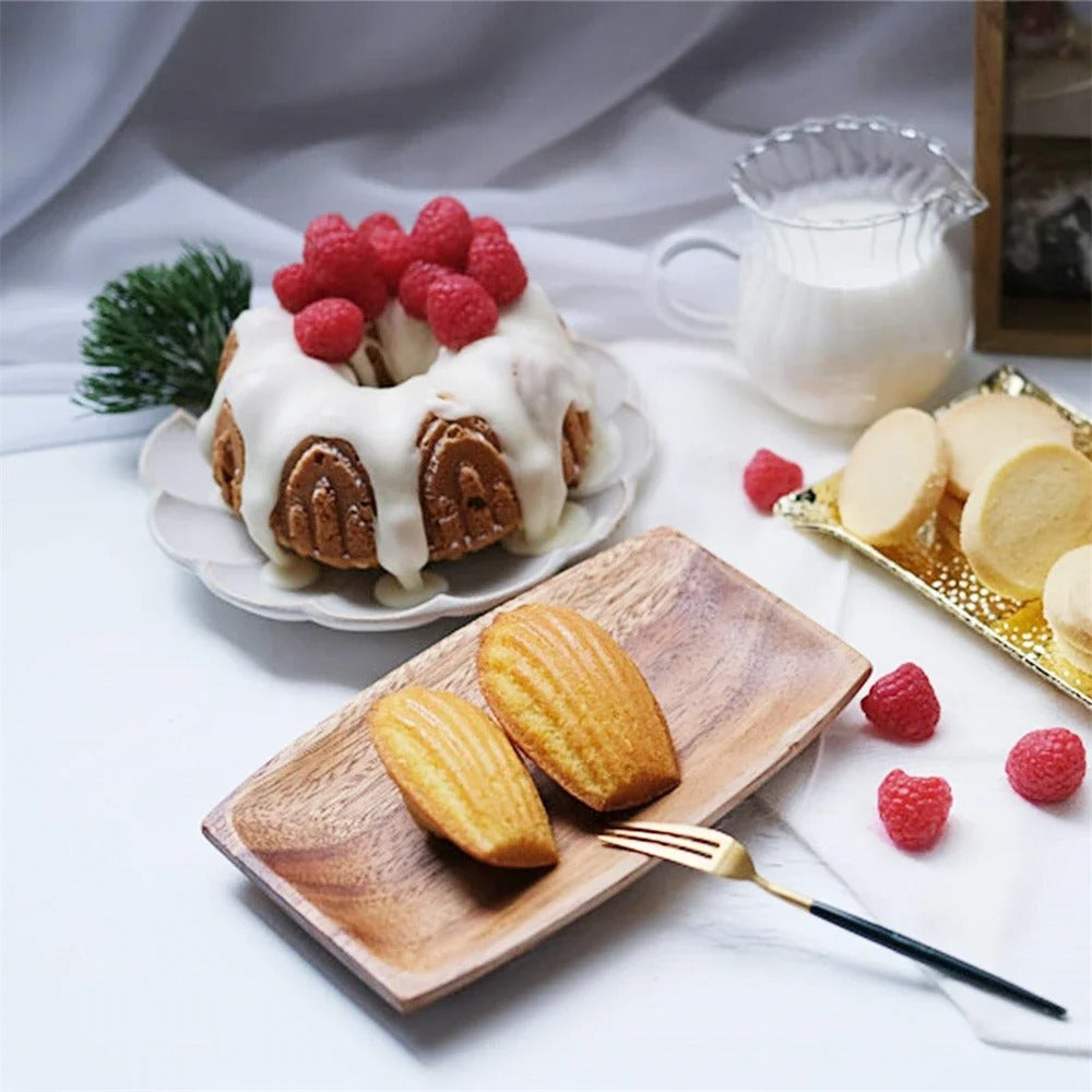 Moule à Madeleines en Silicone avec des madeleines dorées et des framboises fraîches sur une assiette en bois