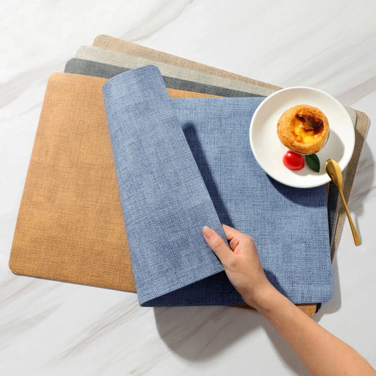 Set de Table Similicuir lot de 4 – Étanche & Anti-Taches. Empilement de sets bleu beige gris, main déroulant un set avec assiette