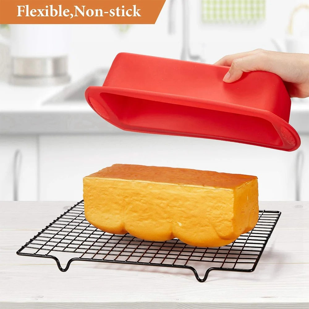 Moule à cake silicone flexible en rouge avec un gâteau bien doré sur une grille de refroidissement