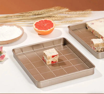 Moule à nougat antiadhésif en métal avec nougat et ingrédients sur une table blanche