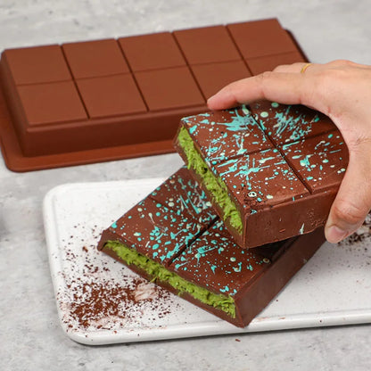 Moule pour faire ses propres tablettes de chocolat avec chocolat vert et bleu décoratif sur un plateau