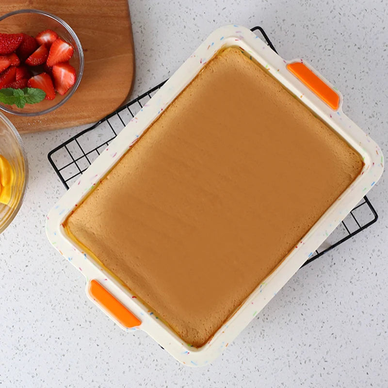 Moule Silicone Antiadhésif – Brownie, Pain & Gâteaux blanc avec des poignées orange sur une grille