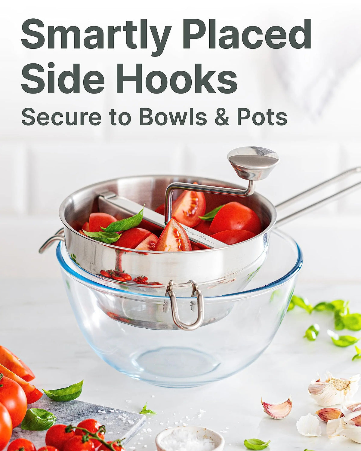 Moulin à légumes à manivelle en acier inoxydable avec tomates fraîches dans un bol en verre
