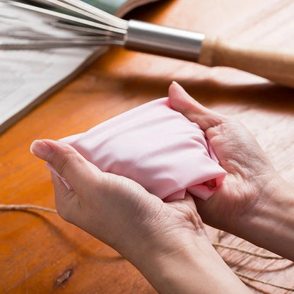 Poche à Douille en Silicone pour Décoration Pâtissière tenue dans les mains avec un fouet en arrière-plan