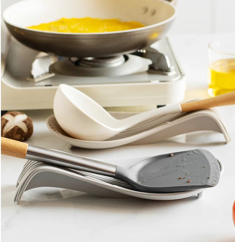 Porte-cuillère en silicone pour cuisine avec des ustensiles de cuisson et une poêle en arrière-plan