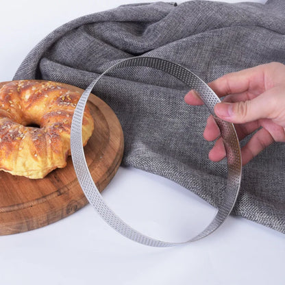 Cercle à Pâtisserie Inox – Moule Rond Pro tenu à la main avec un gâteau en arrière-plan