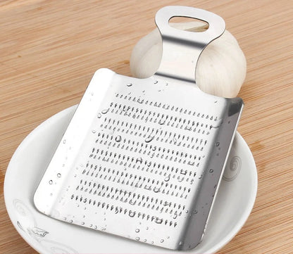 Râpe Inox pour Ail et Gingembre Facile à Utiliser posée sur une assiette en bois