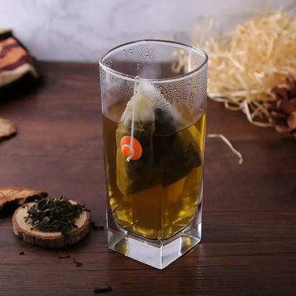 Sachets de Thé Jetables Naturels – Infusion Écologique dans un verre transparent sur une table en bois