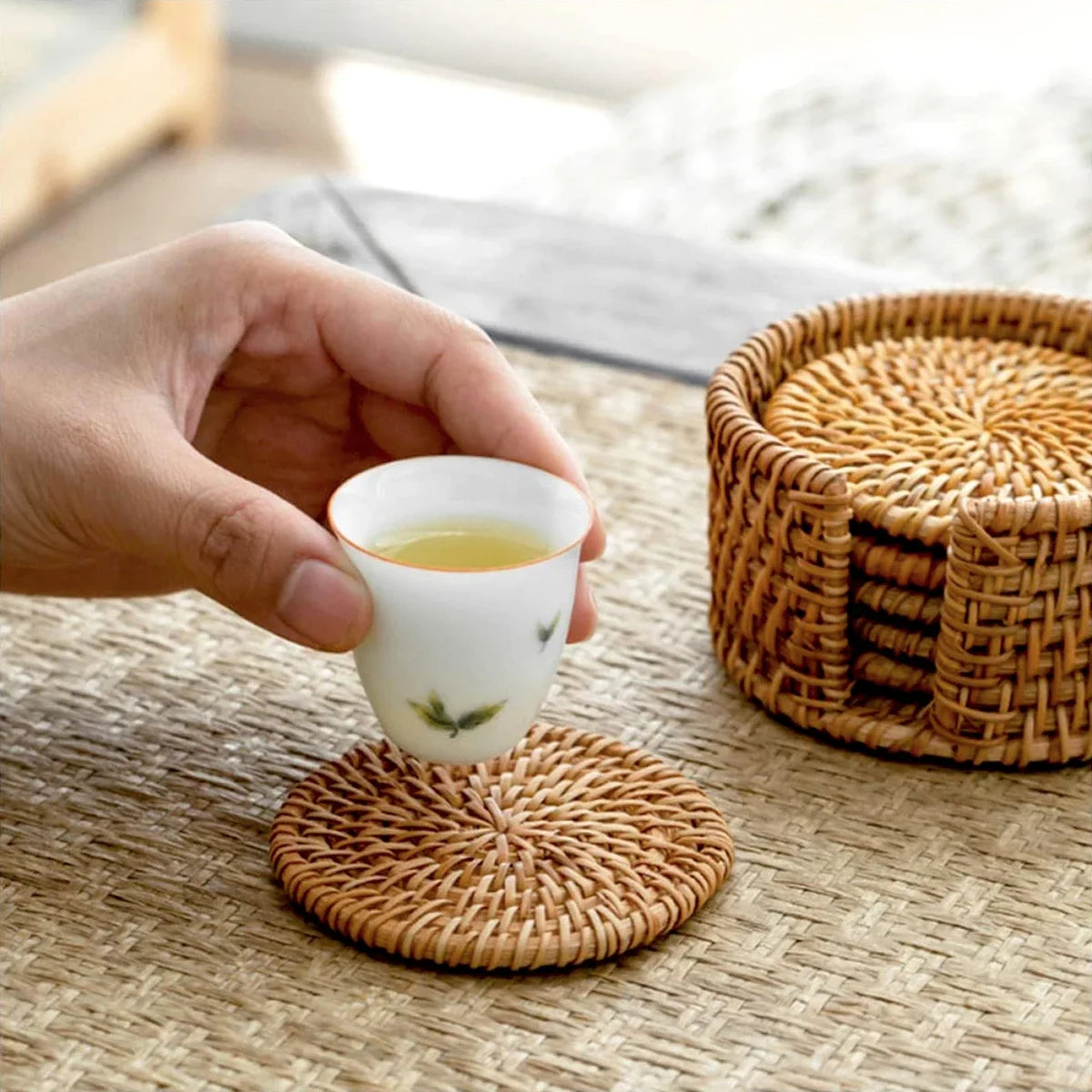 Sous-verres en rotin 8 cm – Set de 6, antidérapants, avec un verre sur un sous-verre sur une table naturelle