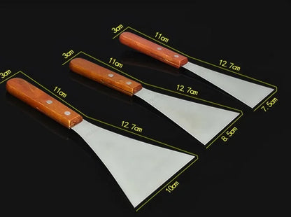 Trois spatules de cuisine inox avec des poignées en bois, disponibles en 28 modèles au choix
