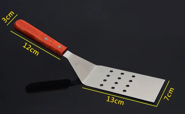 Spatule de Cuisine Inox avec manche en bois, design ergonomique et perforations pour faciliter l'évacuation des liquides.