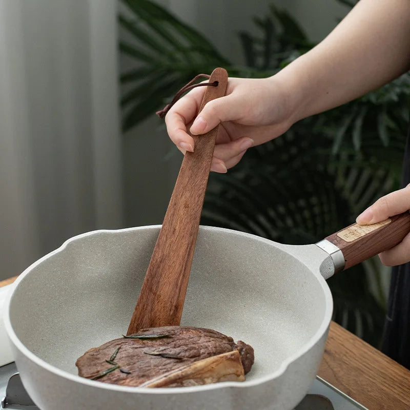 Spatule en Bois de Teck – Résistante à la Chaleur & à l’Huile, utilisée pour retourner un steak dans une poêle de cuisine