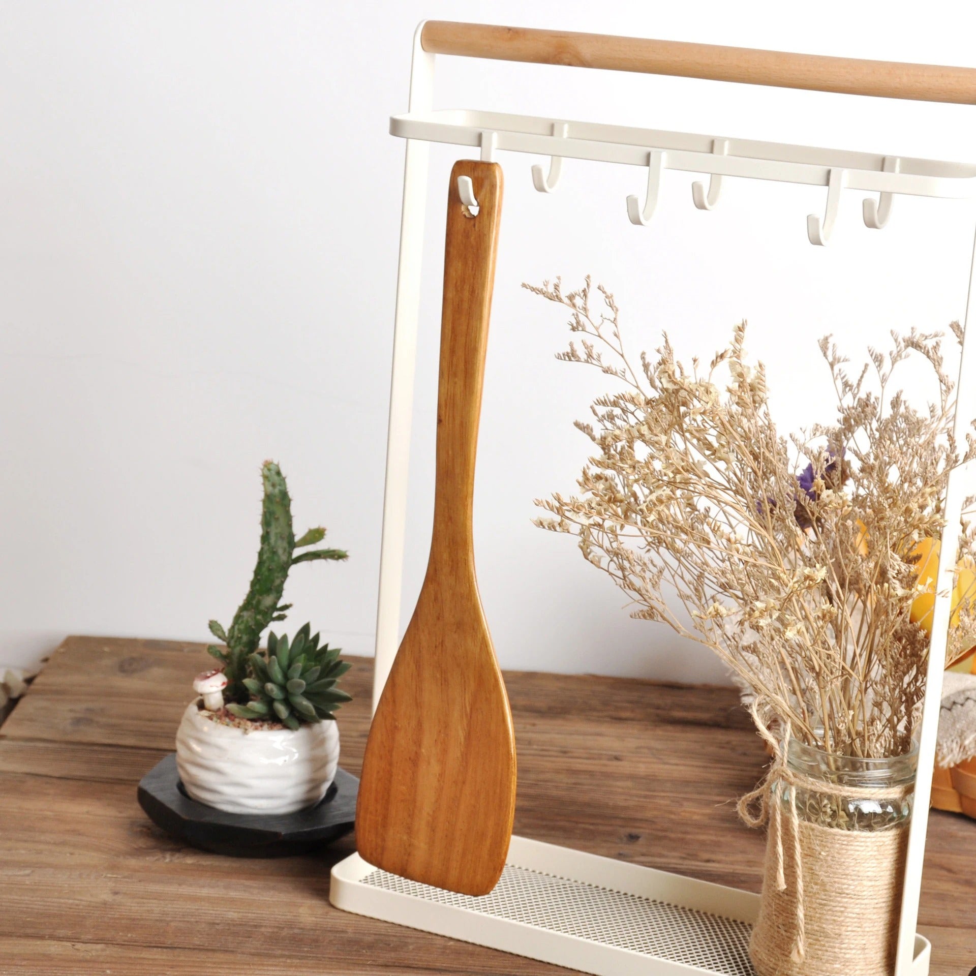 Spatule en Bois Naturel pour Poêle Antiadhésive suspendue avec des fleurs séchées en arrière-plan