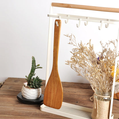 Spatule en Bois Naturel pour Poêle Antiadhésive suspendue avec des fleurs séchées en arrière-plan