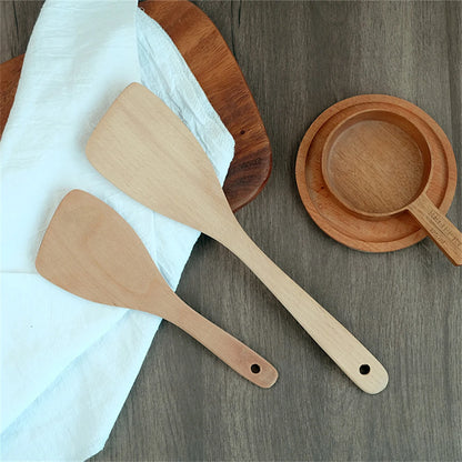 Spatule en Bois Naturel – Ustensile Sain Anti-rayures posées sur table avec assiettes en bois