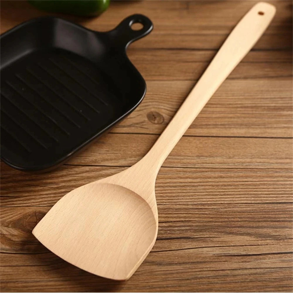 Spatule en Bois Naturel – Ustensile Sain Anti-rayures posée sur table en bois avec poêle noire