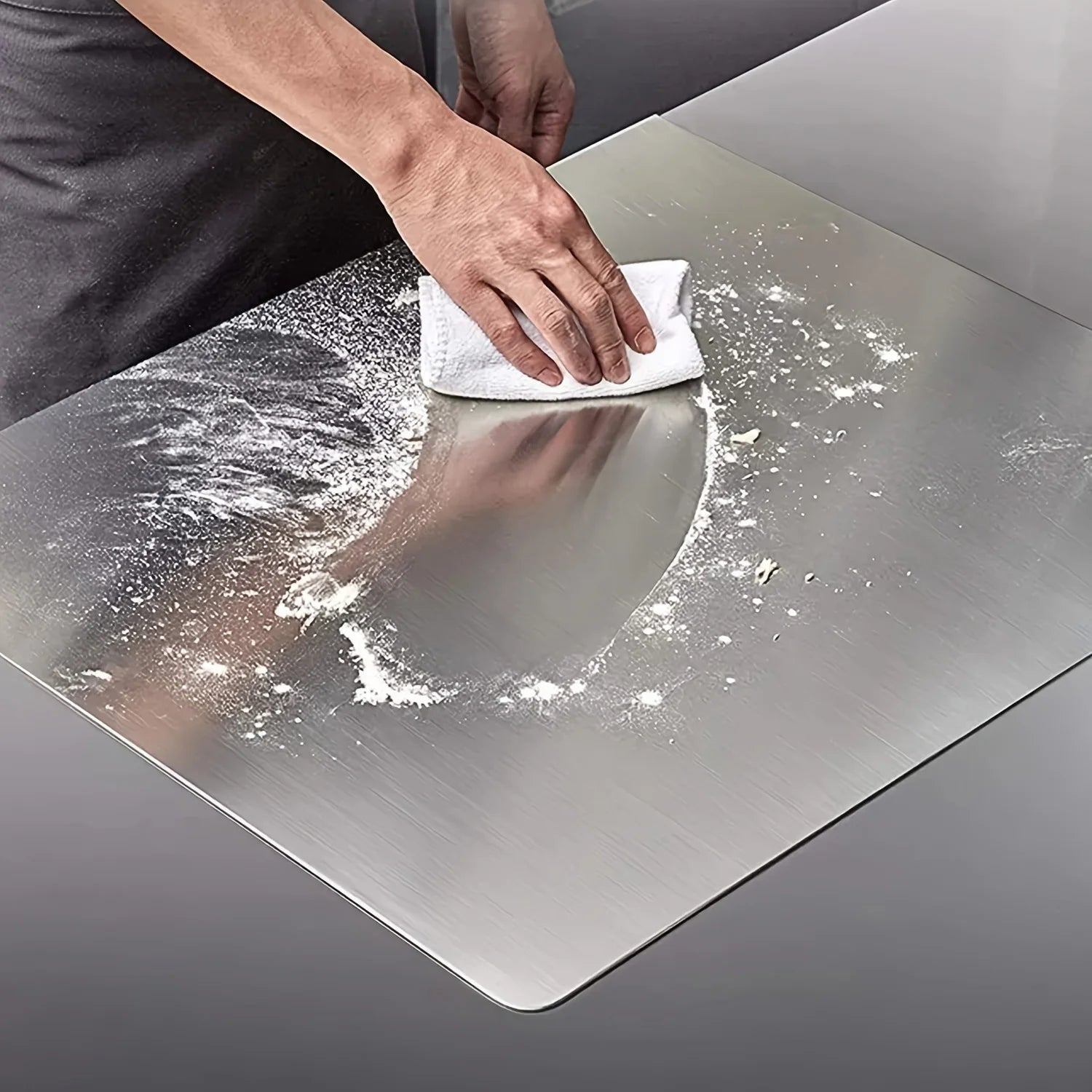 Personne nettoyant une planche à découper en acier inoxydable de qualité supérieure dans une cuisine moderne